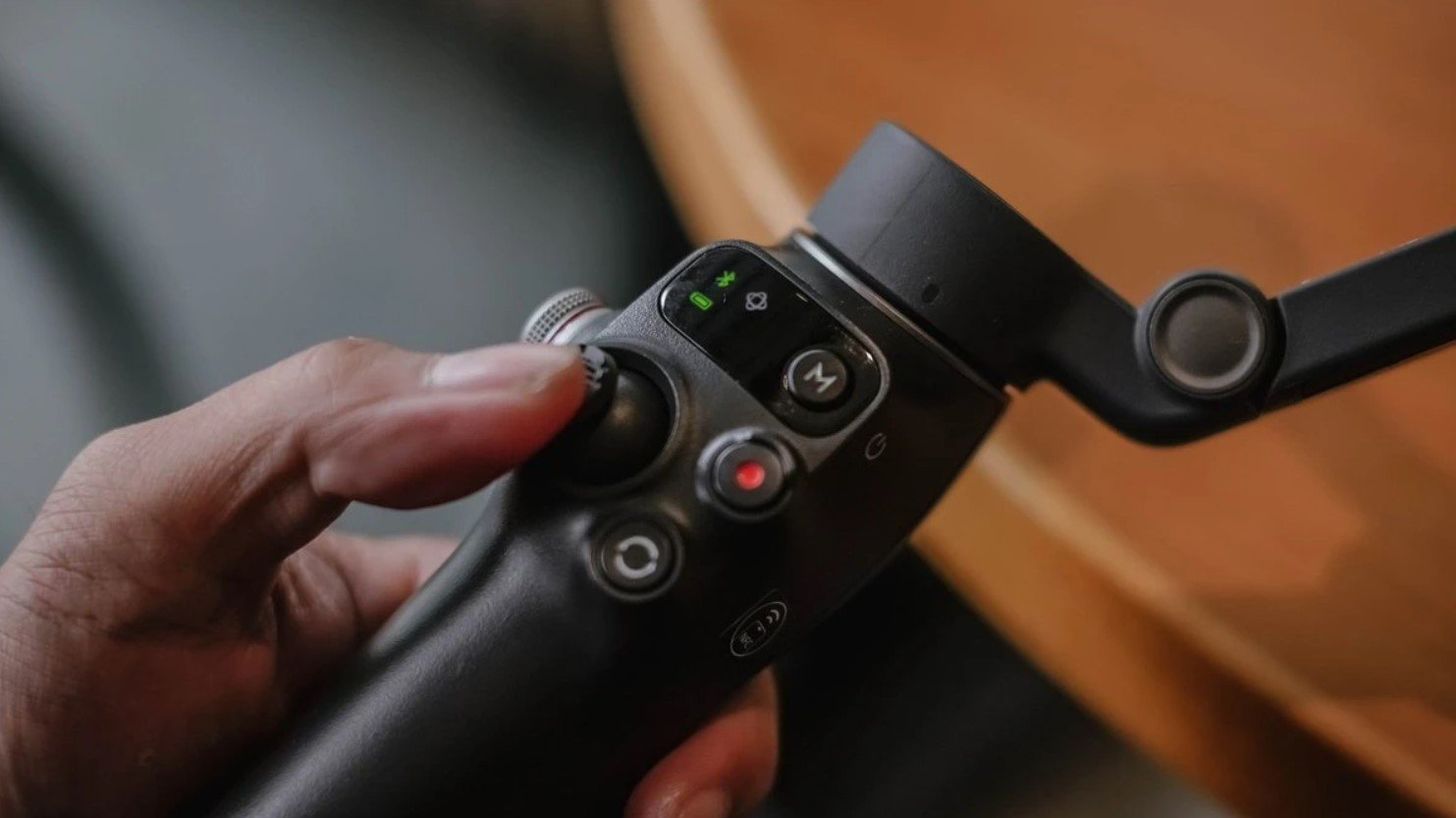 Кнопки й джойстик на рукояті DJI Osmo Mobile 8 під пальцем, вид збоку на панель керування